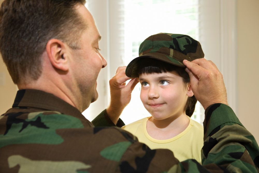 soldier dad lets his child try his uniform cap