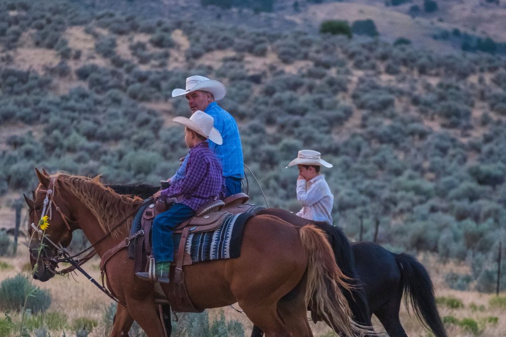 dad and his children wearing cowboy hats and horse riding