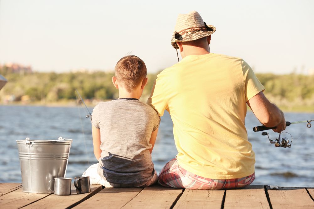 dad and son on fishing near a lake