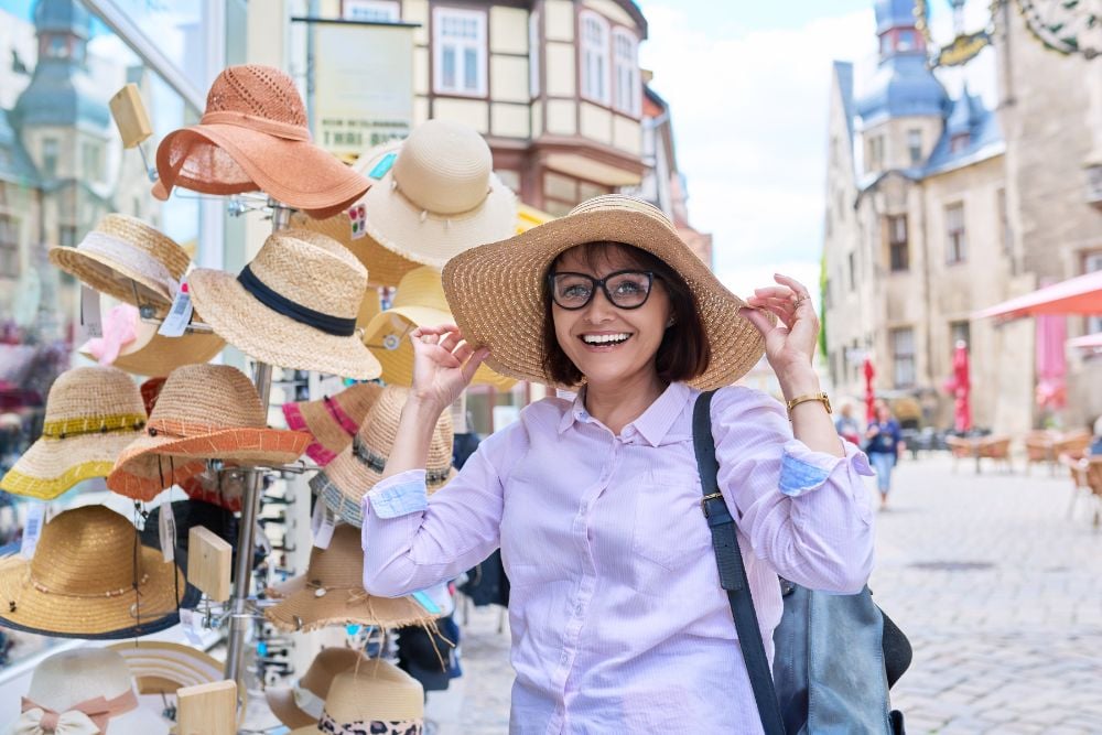 a tourist woman trying a summer hat in local retail store